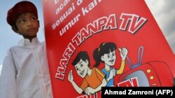 Seorang anak laki-laki memegang poster kampanye "Sehari Tanpa TV" di Jakarta, 20 Juli 2007. KPAI menggelar pertemuan dengan Komisi Penyiaran Indonesia guna membahas tayangan TV ramah anak, Rabu, 2 Juni 2021. (Foto: AFP/Arsip) 