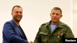 Aleksander Borodai (L), leader of the self-proclaimed "Donetsk People's Republic" shakes hands with rebel leader Aleksander Zakharchenko, during their news conference in Donetsk August 7, 2014.