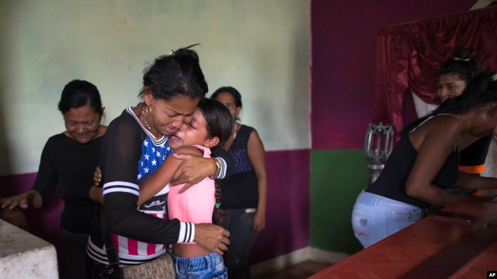 Feliana MÃ¡rquez, la hija de 13 aÃ±os de Daniel MÃ¡rquez, uno de los prisioneros muertos en un motÃ­n e incendio en una cÃ¡rcel de Carabobo, Venezuela, es consolada por su tÃ­a Sorangel GutiÃ©rrez, despuÃ©s que el cuerpo de Daniel fue traÃ­do a la casa de la familia en Valencia, para su funeral. Marzo 29 de 2018.