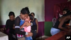 Feliana Márquez, la hija de 13 años de Daniel Márquez, uno de los prisioneros muertos en un motín e incendio en una cárcel de Carabobo, Venezuela, es consolada por su tía Sorangel Gutiérrez, después que el cuerpo de Daniel fue traído a la casa de la familia en Valencia, para su funeral. Marzo 29 de 2018.