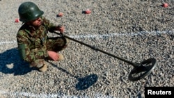 FILE - An Afghan soldier uses a mine detector during a demining drill at Camp Shaheen, a training facility for the Afghan National Army (ANA), west of Mazar-i-Sharif, Dec. 13, 2014. 