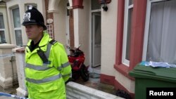 FILE - A police officer stands outside a house after police arrested three men and three women in a counter-terrorism operation linked to the civil war in Syria, in Portsmouth, southern England, Oct. 14, 2014. 