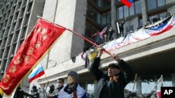 4月7日在乌克兰东部的顿涅茨克，活动人士在一座政府办公楼前挥舞前苏联和俄罗斯的国旗