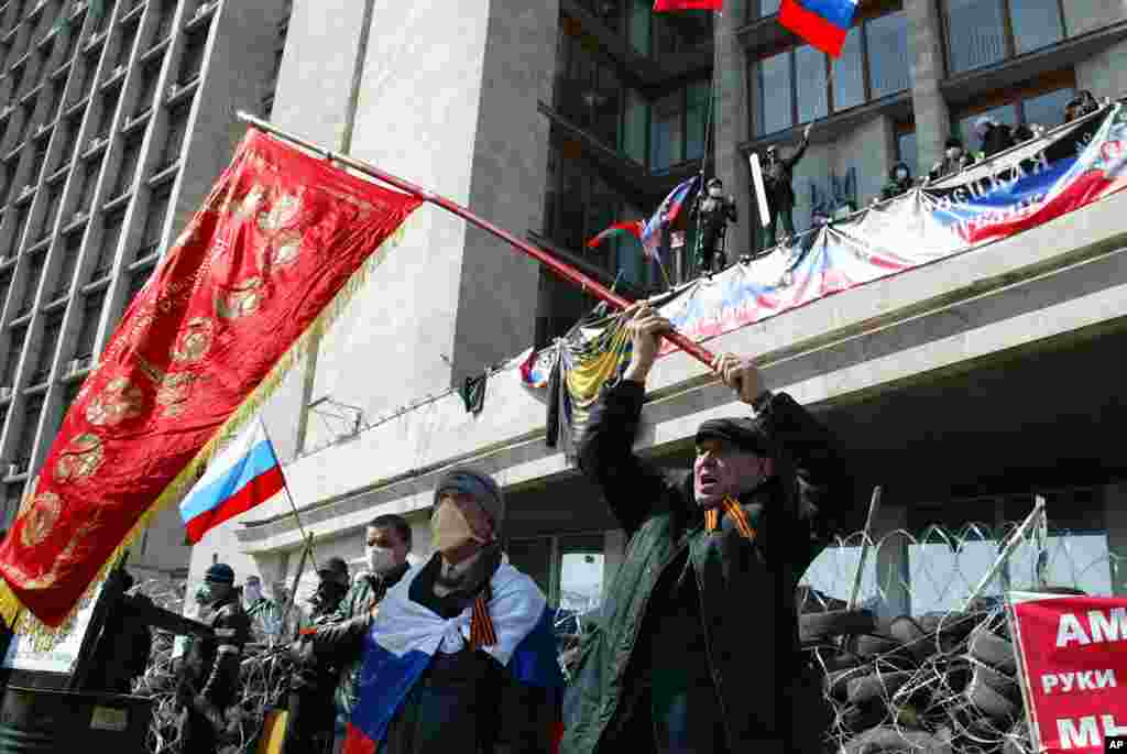 Activistas agitam bandeiras da antiga União Soviética e da Rússica em frente a uma barricada no edifício da administraçãio regional, em Donetsk, Ucrânia, Abril 7, 2014.