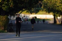 A woman runs in downtown Rome, March 19, 2020. Italian officials are warning they might impose tougher restrictions on mobility, such as jogging.
