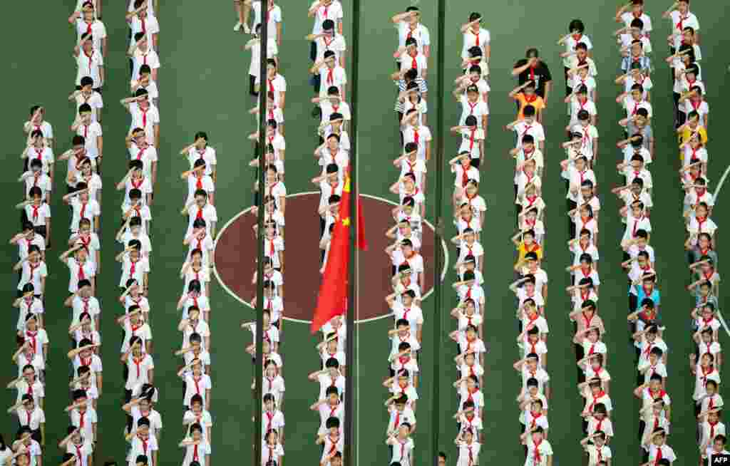 Children line up for a flag-raising ceremony on their first day back to school after the summer holidays, at the playground of a middle school in Shanghai, China.
