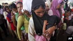 An ethnic Rohingya woman breastfeeds her young child as she waits to receive Muslim headscarfs donated by local residents at a temporary shelter in Aceh province, Indonesia, May 18, 2015.(FILE PHOTO)