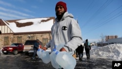 FILE - Lemott Thomas carries free water being distributed at the Lincoln Park United Methodist Church in Flint, Mich., Feb. 3, 2015. Flint's mayor has declared a state of emergency due to problems with the city's water system caused by using water from the Flint River, saying the city needs more federal help.