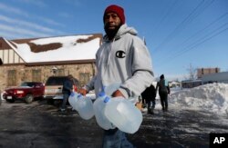 FILE - Lemott Thomas carries free water being distributed at the Lincoln Park United Methodist Church in Flint, Mich., Feb. 3, 2015.