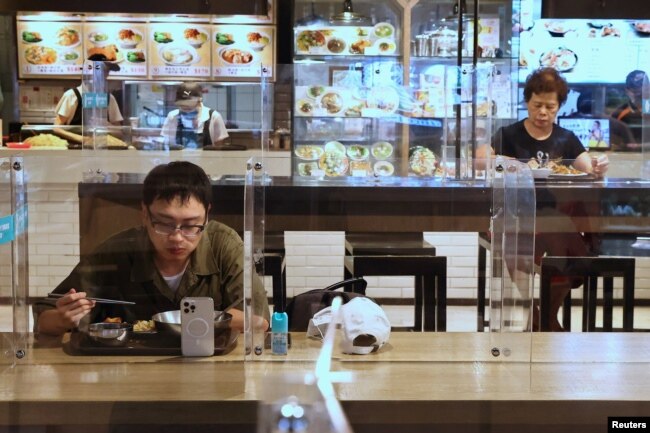 台北餐館在新冠疫情期間採取措施，吃午餐的顧客之間隔著塑料屏並保持距離。 （2021年5月12日）