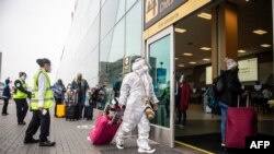 A passenger wearing a protective suit and face masks enters to the Jorge Chavez International Airport in Callao, Peru, in Oct. 5, 2020, as international flights resume after more than six months due to the COVID-19 coronavirus pandemic. 