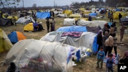 Migrants stand by tents in a camp set up near the Turkish-Greek border in Pazarkule, Edirne region, Turkey, March 10, 2020. 