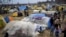 Migrants stand by tents in a camp set up near the Turkish-Greek border in Pazarkule, Edirne region, Turkey, March 10, 2020. 