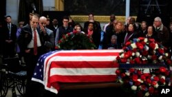 Mantan Senator Bob Dole memberi hormat di hadapan peti jenazah mantan presiden George H.W. Bush yang diselimuti bendera dan disemayamkan di Gedung Capitol di Washington, 4 Desember 2018.