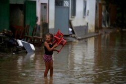 A girl carries a chair in flood waters in Itapetinga, Bahia state, Brazil, Dec. 28, 2021.