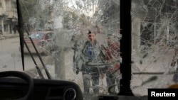 Boys are pictured through a broken windshield as they stand on a street in Aleppo, Feb. 28, 2013.