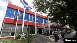 FILE - People sit outside the building which used to house a Coca-Cola bottling plant before the 1959 revolution in Havana.