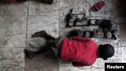 A boy suffering from polio crawls beside his braces in Kinshasa, capital of the Democratic Republic of the Congo, November 29, 2011. 