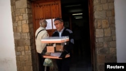 Seorang petugas pemilu membawa kota suara sementara seorang pria membaca hasil pemilu di pintu TPS, sehari setelah pemilu berlangsung di Spanyol, di Ronda, Spanyol selatan, 21 Desember 2015. 