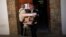 An election worker carries a ballot box while a man looks at the results on the door outside a polling station, a day after the most fragmented national election in Spain's history, in Ronda, southern Spain, Dec. 21, 2015. 