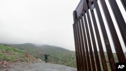 FILE - Border Patrol agent Vincent Pirro looks on near where a border wall ends that separates the cities of Tijuana, Mexico, and San Diego, Feb. 5, 2019, in San Diego. 