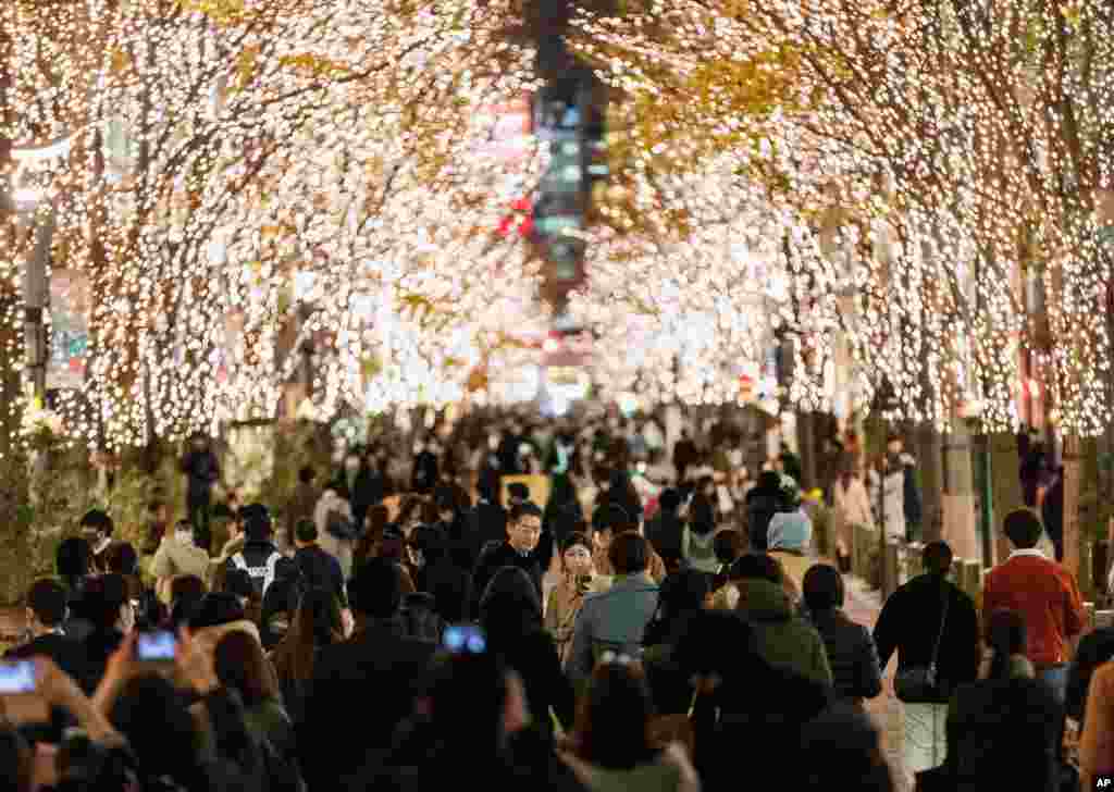 People walk along a street decorated with lights on trees during &quot;vehicle-free hours&quot; in Tokyo, Japan.