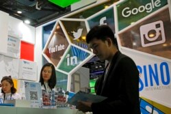 FILE - A visitor seeks information at a social network company booth which enables people to connect global clients during the 2016 Global Mobile Internet Conference in Beijing, April 28, 2016.