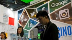 FILE - A visitor seeks information at a social network company booth that enables people to connect global clients during the 2016 Global Mobile Internet Conference in Beijing, April 28, 2016.