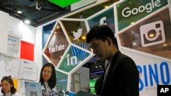 FILE - A visitor seeks information at a social network company booth that enables people to connect global clients during the 2016 Global Mobile Internet Conference in Beijing, April 28, 2016.