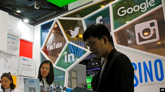 FILE - A visitor seeks information at a social network company booth that enables people to connect global clients during the 2016 Global Mobile Internet Conference in Beijing, April 28, 2016.