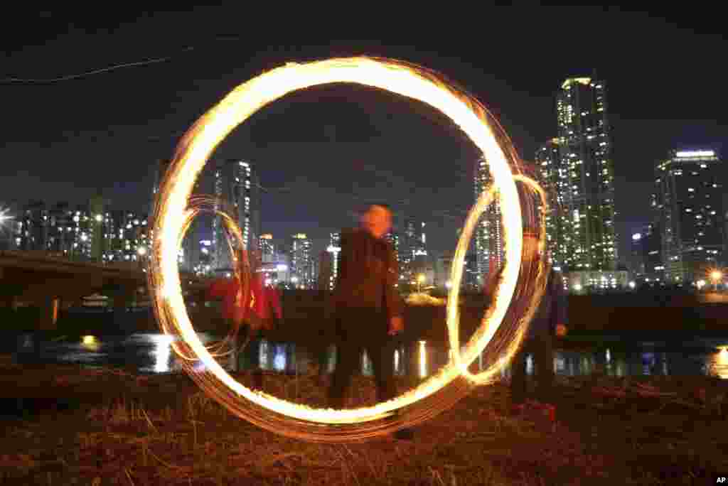 People twirl cans filled with burning wood chips and straw to celebrate the first full moon of the Lunar New Year in Seoul, South Korea.