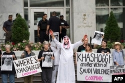 A demonstrator dressed as Saudi Arabian Crown Prince Mohammed bin Salman, center, with blood on his hands protests with others outside the Saudi Embassy in Washington, Oct. 10, 2018.