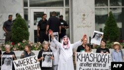 A demonstrator dressed as Saudi Arabian Crown Prince Mohammed bin Salman, center, with blood on his hands protests with others outside the Saudi Embassy in Washington, Oct. 10, 2018.