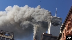 FILE - Smoke rises from the burning twin towers of the World Trade Center after hijacked planes crashed into them, in New York City, Sept. 11, 2001.