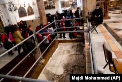 In this Thursday, Dec. 6, 2018 photo, visitors walk by a repaired part of a mosaic inside the Church of the Nativity.