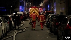 Un policier et des pompiers près de l'immeuble où s'est déclaré l'incendie au 16è arrondissement, Paris, le 5 février 2019.
