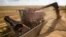 FILE - A combine harvester machine loads grain onto a transport truck near the southern Ukranian city of Nikolaev.