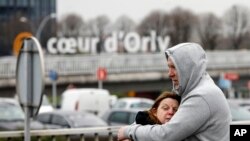 Travelers hug outside Orly Airport, south of Paris, March, 18, 2017. A man was shot to death Saturday after trying to seize the weapon of a soldier guarding Paris' Orly Airport, prompting a partial evacuation of the terminal, police said. 