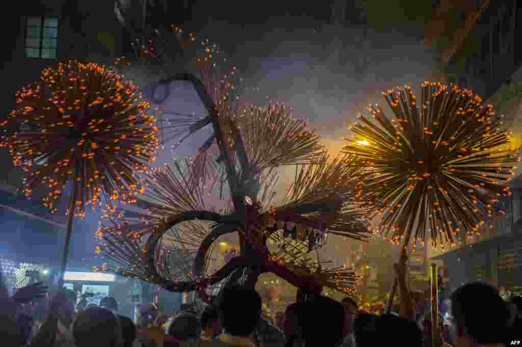 Members of the fire dragon dance team hold up the &#39;dragon&#39; as it winds through the narrow streets and houses during the Tai Hang Fire Dragon Dance in Hong Kon.