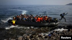 FILE- An Afghan migrant jumps off an overcrowded raft onto a beach in the Greek island of Lesbos, Greece.