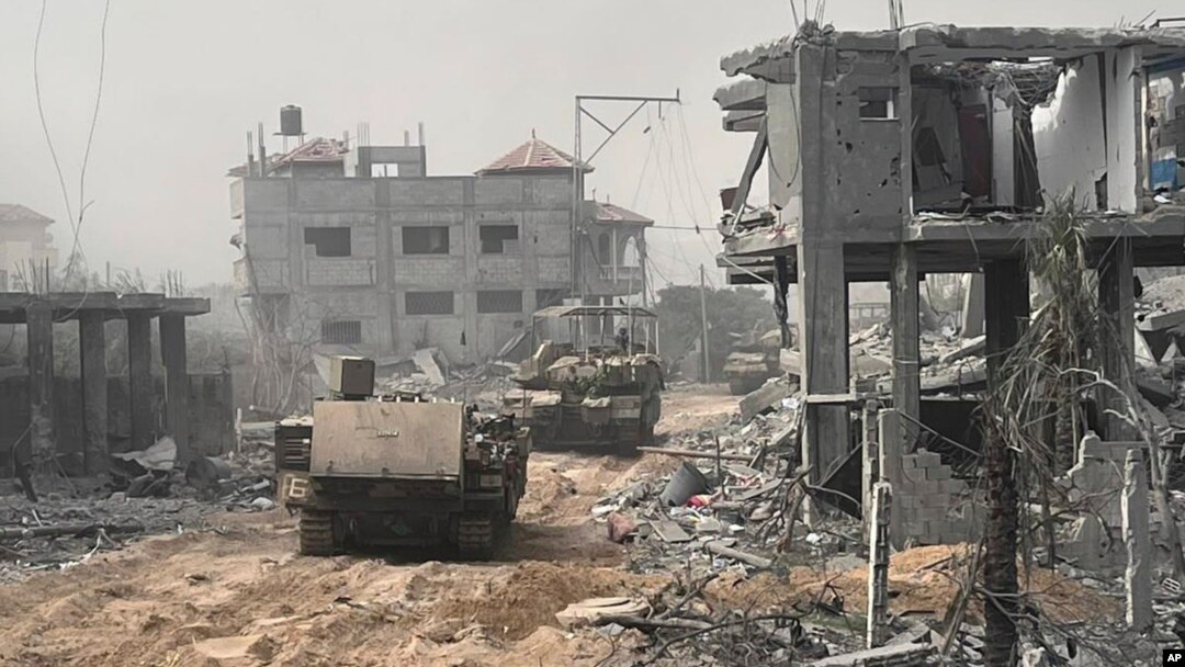 En esta imagen sin fecha distribuida por el ejército israelí, vehículos blindados de transporte de tropas avanzan entre edificios destruidos durante una operación terrestre en la Franja de Gaza.