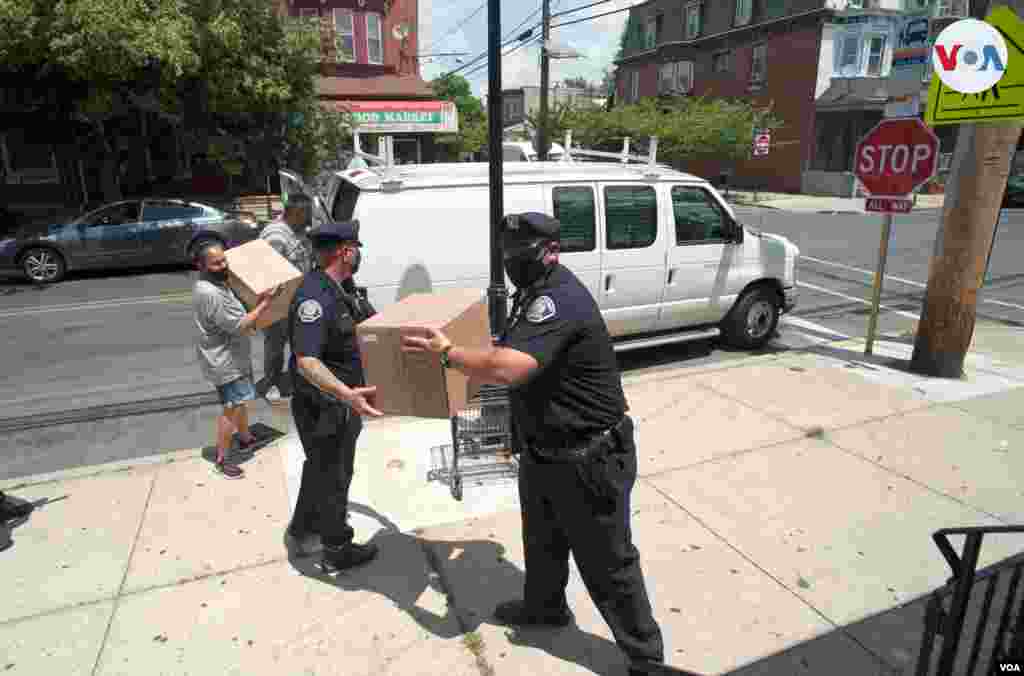 Oficiales de polic&#237;a ayudan al pastor Carmelo Ure&#241;a a bajar y repartir donaciones para la comunidad de Camden, Nueva Jersey.