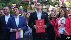 National Assembly President Jorge Rodriguez, center, holds a bill that codifies economic sanctions as a crime against humanity and allows prosecution of anyone who expresses support for the measures, in Caracas, Venezuela, Nov. 28, 2024.