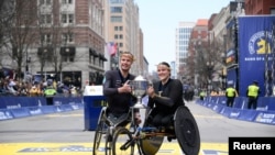 Marcel Hug of Switzerland and Eden Rainbow Cooper of Great Britain pose with the winner trophy after winning their respective wheelchair divisions of the 2024 Boston Marathon, in Boston, MA, USA, April 15, 2024. (Eric Canha-USA TODAY Sports)