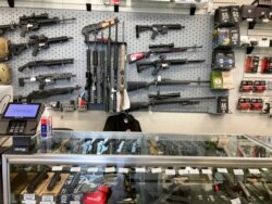 FILE - Weapons hang in a gun shop, Feb. 19, 2021, in Salem, Ore.