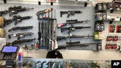 FILE - Weapons hang in a gun shop, Feb. 19, 2021, in Salem, Ore. 