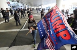 A woman who supports President Donald Trump's executive order barring entry to the U.S. by seven Muslim-majority countries waves a Trump campaign flag at Los Angeles International Airport, Feb. 4, 2017.