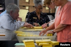 Petugas pemilihan memproses surat suara setelah pemungutan suara ditutup untuk pemilihan paruh waktu AS di pusat tabulasi di Pusat Pemilihan dan Pendaftaran Kabupaten Cobb di Marietta, Georgia, AS, 8 November 2022. (Foto: REUTERS/Cheney Orr)