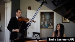 Musicians David Shenton and Erin Shields perform inside their home in the Queens borough of New York on March 30, 2021. (AP Photo/Emily Leshner)