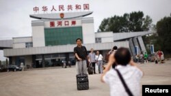 Seorang turis China berpose untuk foto di perbatasan antara China dan Korea Utara, di Hunchun, provinsi Jilin, 29 Agustus 2011. (Foto: dok).